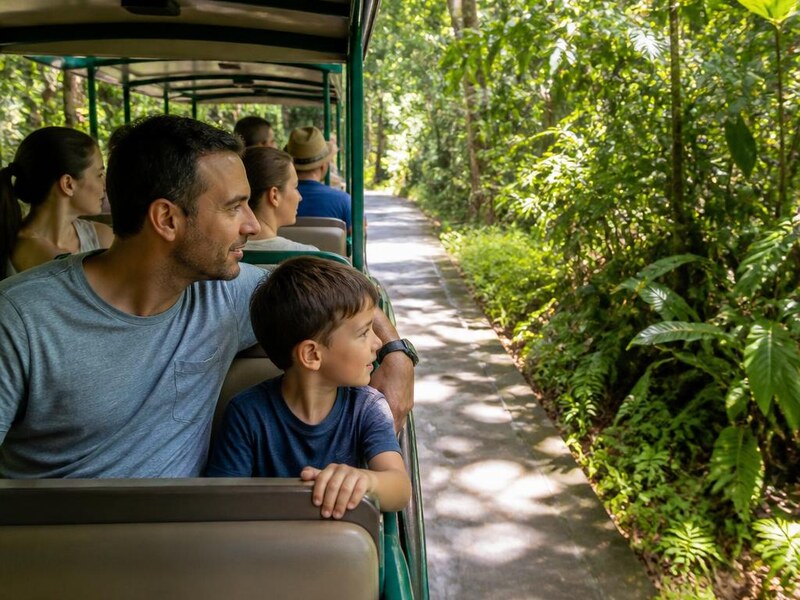 Family riding an electric shuttle tram through the jungle at Jaguar Park near Tulum